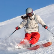 Frau auf Skier fährt die Piste herunter.